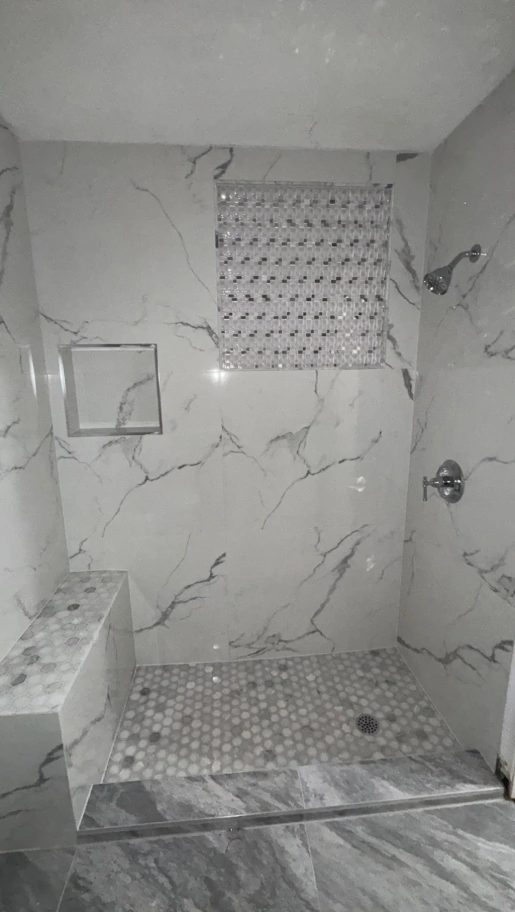 Walk-in shower with Carrara marble wall tiles, penny mosaic floor, and built-in bench